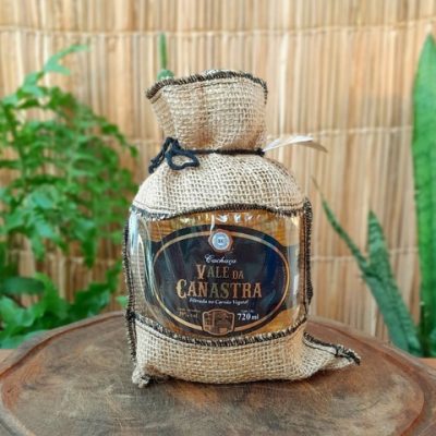 Cachaça Vale da Canastra com capa de juta sobre mesa de madeira.