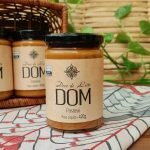 Doce de leite DOM em pote médio com 420 gramas, sobre mesa de madeira.