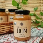 Doce de leite DOM em pote médio com 700 gramas, sobre mesa de madeira.