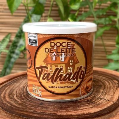 Doce de leite talhado em lata de 800 gramas, sobre tábua de madeira.