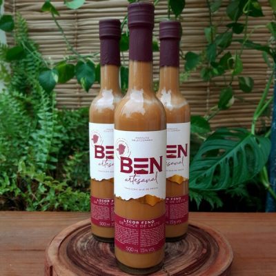 Licor Ben em garrafa com 500 ml, sobre mesa de madeira.