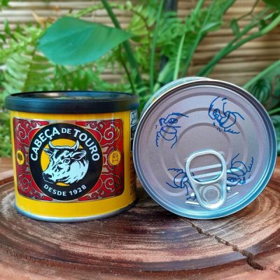 Manteiga Cabeça de Touro em lata com 200 gramas, sobre mesa de madeira.