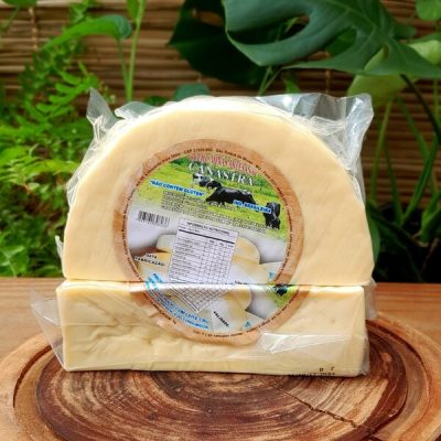 Queijo Canastra artesanal em meia peça embalada a vácuo, sobre mesa de madeira.