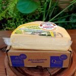 Queijo Canastra Reinaldo em meia peça embalada à vácuo, sobre mesa de madeira.