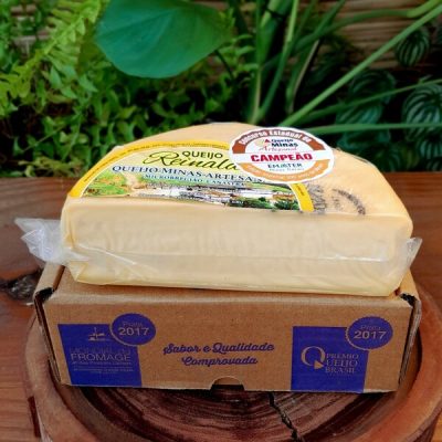 Queijo Canastra Reinaldo em meia peça embalada à vácuo, sobre mesa de madeira.