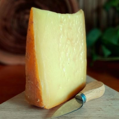 Queijo tipo Comté Serra das Antas fatiado sobre tábua de madeira.