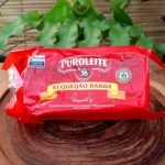 Requeijão de corte Puro Leite em embalagem com aproximadamente 400 gramas, sobre mesa de madeira.