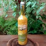 Tiuba banana em garrafa com 700 ml sobre mesa de madeira.