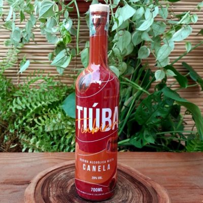 Tiuba canelinha em garrafa com 700 ml sobre mesa de madeira.