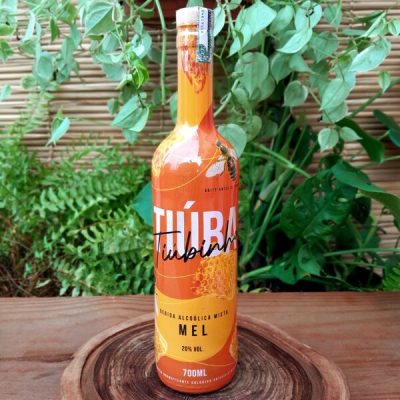 Tiuba mel em garrafa com 700 ml sobre mesa de madeira.