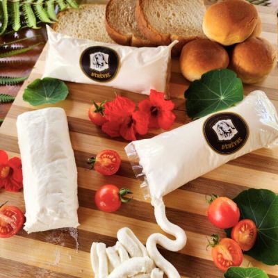 Creme de queijo boursin de cabra sobre tábua de madeira com pães e tomatinhos.