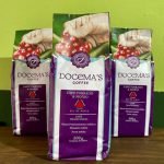 Café arábica em pacotes sobre mesa de madeira.