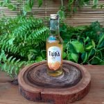 Tiúba mel em garrafa de 275 ml sobre mesa de madeira.