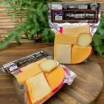 Kit de queijos finos embalados à vácuo sobre tábua de madeira.