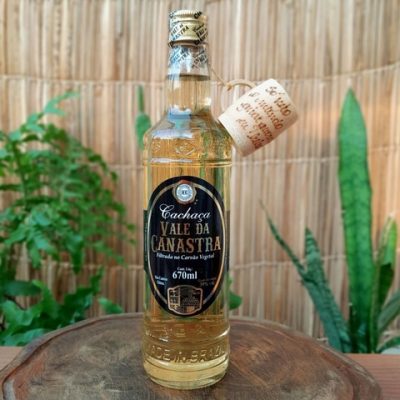 Cachaça vale da Canastra com copinho, sobre mesa de madeira.