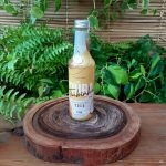 Licor de coco Tiúba em garrafa de 275 ml sobre mesa de madeira.