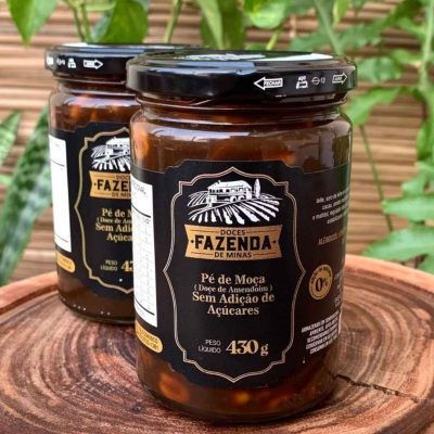 Pé de moça sem açúcar em pote de 430 gramas sobre mesa de madeira.