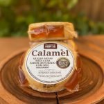 Queijo calambau meia cura defumado com mel, embalado sobre tábua de madeira.