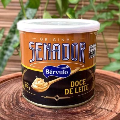 Doce de leite Senador em lata de 800 gramas sobre tábua de madeira.