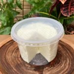 Queijo minas frescal Majestic em embalagem plástica transparente sobre mesa de madeira.