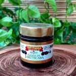Geleia de jabuticaba em pote de 300 gramas, sobre mesa de madeira.
