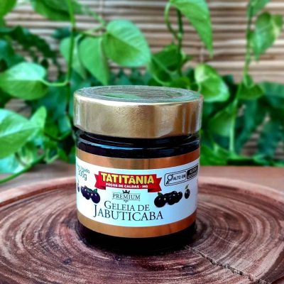 Geleia de jabuticaba em pote de 300 gramas, sobre mesa de madeira.