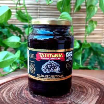 Geleia de jabuticaba com 680 gramas em pote de vidro sobre mesa de madeira.