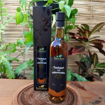 Cachaça com jabuticaba Sabarabuçu em garrafa de 500 ml sobre mesa de madeira.