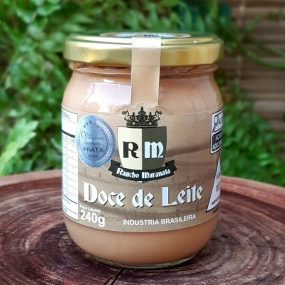Doce de leite Rancho Maranata em pote de vidro com 240 gramas sobre mesa de madeira.