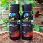 Molho de jabuticaba com pimenta Sabarabuçu, em frasco de plástico com 180 ml sobre mesa de madeira.