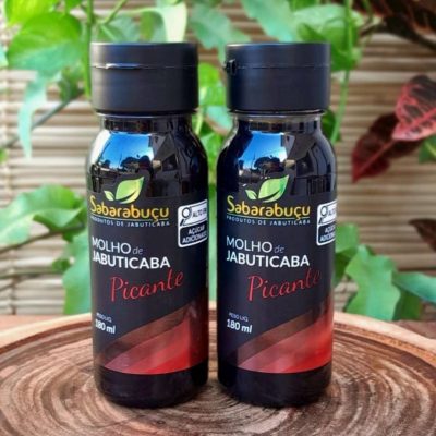 Molho de jabuticaba com pimenta Sabarabuçu, em frasco de plástico com 180 ml sobre mesa de madeira.