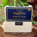 Queijo coalho Dourado em barra, em peça inteira com aproximadamente 450 gramas, sobre mesa de madeira.