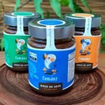 Doce de leite Comanz sobre mesa de madeira. 3 poyes de vidro.