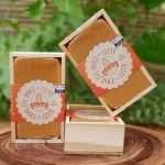 Doce de leite Dona lázara em caixinha de madeira com 220 gramas, sobre mesa de madeira.