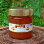 Geleia de laranja com pimenta Tatitânia em pote de 300 gramas sobre mesa de madeira.