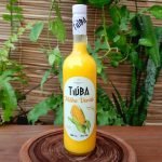 Licor de milho verde Tiúba sobre mesa de madeira.