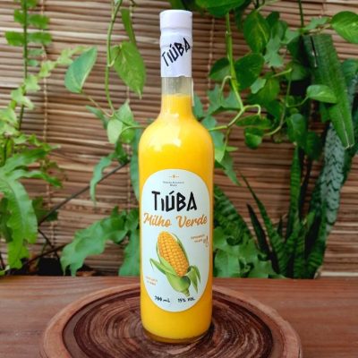 Licor de milho verde Tiúba sobre mesa de madeira.