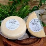Queijo Vô Bastião meia cura Serra das Antas sobre mesa de madeira.