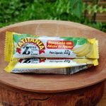 Bananinha sem açúcar Tatitânia, em embalagem individual com 22 gramas, sobre mesa de madeira.