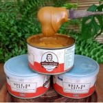 Doce de leite Dona Lázara tradicional em lata de 400 gramas sobre mesa de madeira.