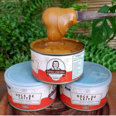 Doce de leite Dona Lázara tradicional em lata de 400 gramas sobre mesa de madeira.