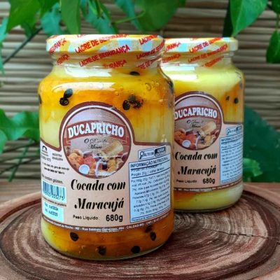 Cocada cremosa com maracujá em pote com 680 gramas sobre mesa de madeira.