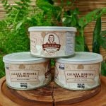 Cocada branca Dona Lázara em lata com 400 gramas, sobre mesa de madeira.