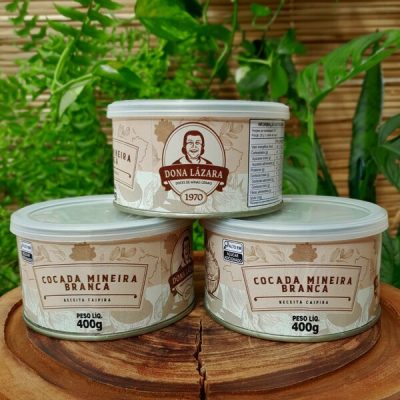 Cocada branca Dona Lázara em lata com 400 gramas, sobre mesa de madeira.