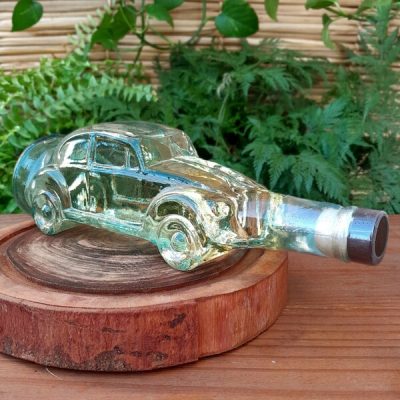 Cachaça Vale da Canastra ouro, com garrafa em formato de fusca, sobre mesa de madeira.