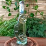 Cachaça Vale da Canastra ouro em garrafa em formato de Fusca, sobre mesa de madeira.