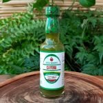 Molho de pimenta Cayena em embalagem de vidro com 60 ml sobre mesa de madeira.