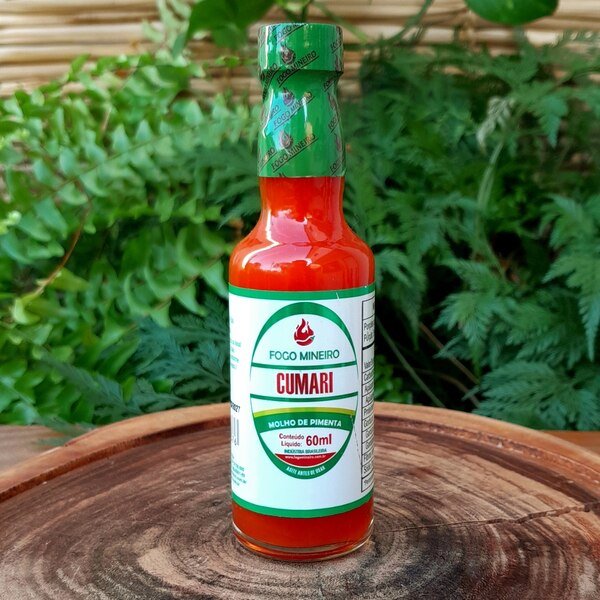 molho-de-pimenta-cumari Molho de pimenta Cumari em embalagem de vidro com 60 ml sobre mesa de madeira.