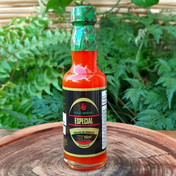 molho-de-pimenta-especial-fogo-mineiro Molho de pimenta especial Fogo Mineiro em embalagem de vidro com 60 ml sobre mesa de madeira.