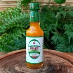 Molho de pimenta Habanero em embalagem de vidro com 60 ml sobre mesa de madeira.